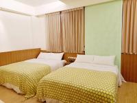 a bedroom with two beds with yellow and white sheets at 水社海民宿 in Yuchi