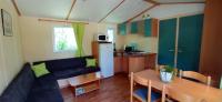 a living room with a couch and a table and a kitchen at CAMPING LE BEL AIR Mobil home L&#39;OLIVIER 4 personnes in Limogne-en-Quercy