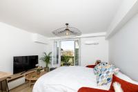 a white bedroom with a large bed and a tv at Superbe T2 Juan Les Pins 300m des plages in Antibes