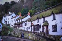 un grupo de casas blancas con techos de hierba en una calle en Rising Sun Hotel, en Lynmouth