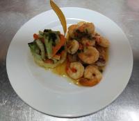 um prato branco com camarão e legumes numa mesa em Hotel Cabinas el Tecal em Uvita