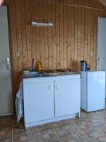a kitchen with white cabinets and a sink and a refrigerator at Au petit chalet d&#39;Illiers Combray in Illiers