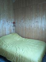 a bed in a room with a wooden wall at Au petit chalet d&#39;Illiers Combray in Illiers