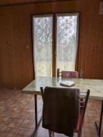 a table and chairs in a room with two windows at Au petit chalet d&#39;Illiers Combray in Illiers