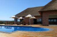 奥茨胡恩Klein Karoo Game Lodge的一座带游泳池的建筑,配有遮阳伞