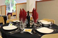 a black table with a bottle of wine and red flowers at Azureva Ronce les Bains in Ronce-les-Bains