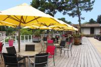 a patio with tables and chairs with yellow umbrellas at Azureva Ronce les Bains in Ronce-les-Bains