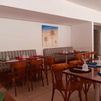 ein Restaurant mit Tischen und Stühlen und einem Gemälde von Palmen in der Unterkunft Apartamento Reserva do Sahy - Condomínio Aldeia dos Reis in Mangaratiba