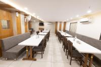 Un comedor con mesas largas y sillas. en HOTEL THE GRAND DIPAK, en Junagadh