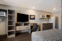 Un dormitorio con una cama y un escritorio con televisión. en WoodSpring Suites Grand Rapids Kentwood, en Grand Rapids