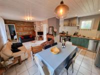 a kitchen and a living room with a table and a couch at La Cabane aux Acacias~vacances nature et au calme in Mézos
