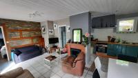 a living room with a couch and a kitchen at La Cabane aux Acacias~vacances nature et au calme in Mézos