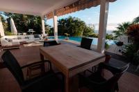 a wooden table and chairs on a patio with a pool at YOU WELCOME VILLA in Case-Pilote