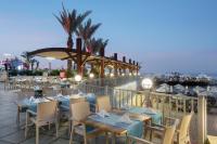 un restaurant sur la plage avec tables et chaises dans l'établissement Granada Luxury Okurcalar, à Okurcalar