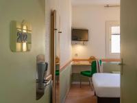Zimmer mit einem Schreibtisch und einem Tisch mit einem grünen Stuhl in der Unterkunft ibis budget Menton Bord de Mer in Menton