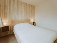 a bedroom with a white bed and wooden walls at Apartment Rodenbach by Interhome in De Haan