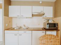 a kitchen with white cabinets and a sink and a microwave at Studio Zeeduin by Interhome in Bredene