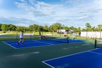 drei Personen spielen Tennis auf einem Tennisplatz in der Unterkunft Gulf Shores RV Resort in Gulf Shores