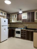 Una cocina con gabinetes marrones y un refrigerador blanco. en Casa Mía, en Resistencia