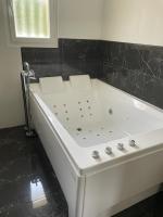 a white tub in a bathroom with a black tile wall at Villa Emma 10 &#47; 12 personnes in Grignan