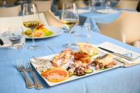 um prato de comida numa mesa com copos de vinho em Hotel Santa Caterina em Palinuro
