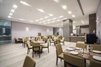 Un restaurante con mesas y sillas y una cocina. en Enala Hotel - Al Khobar, en Al Khobar