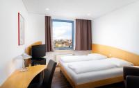 Una habitación de hotel con una cama, un escritorio y una ventana. en Mainstreet Hotel, en Dietzenbach