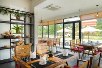 a restaurant with wooden tables and chairs and windows at Sala Siem Reap Hotel in Siem Reap