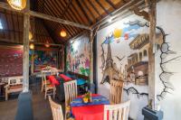 a restaurant with tables and chairs and a wall with a mural at Bamboo Ubud Hostel in Ubud