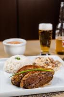 a plate with meat and rice and a glass of beer at Hotel Caiuá in Umuarama