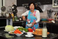 a woman standing in a kitchen preparing food at Yunju House in Jiaoxi