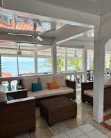 een afgeschermde veranda met een bank en stoelen bij Los Delfines Hotel & Dive Center in Little Corn Island
