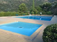 a swimming pool with blue water in a yard at T3 Le Bagnolet Les Mas de Pramousquier in Le Lavandou