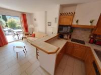 a kitchen and living room with a couch and a tv at T3 Le Bagnolet Les Mas de Pramousquier in Le Lavandou