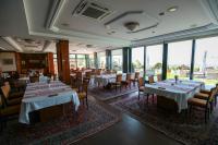 a dining room with tables and chairs and windows at Hotel Villa Breg in Vršac