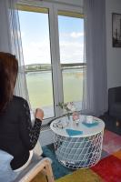 a woman sitting in a chair looking out of a window at Panorama Apartman in Velence