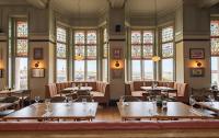 a restaurant with tables and chairs and stained glass windows at Cliftonville Hotel in Cromer