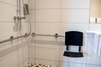 a shower with a black chair in a bathroom at Hotel Restaurant Le Coquelicot in Burnhaupt-le-Haut