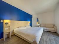 Un dormitorio con una cama blanca y una pared azul. en Hotel De La Gare, en Quimper