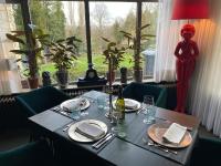 een tafel met borden en glazen en een rood beeld in een raam bij De Post B&B Restaurant in Klimmen
