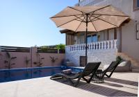 a patio with two chairs and an umbrella next to a pool at Jasmine loft luxury 1 in Kokkini Khanion
