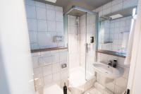 a white bathroom with a shower and a sink at City Park Hotel in Frankfurt Oder
