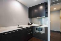 a kitchen with black cabinets and white counter tops at Chatrium Hotel Riverside Bangkok in Bangkok