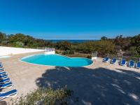 a swimming pool with lounge chairs and a view of the ocean at Holiday Home Chez Béatrice et Pascal by Interhome in Belgodère