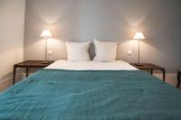 a bedroom with a green bed with two lamps at L&#39;appartement du Cellier in Pommard