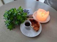 a table with a candle and a plate with a cup of coffee and toast at Kerletty, la mer, les embruns, à 250 m des plages in Plouguerneau