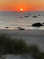 a sunset on a beach with boats in the water at Kerletty, la mer, les embruns, à 250 m des plages in Plouguerneau