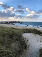 a sandy beach with grass and the ocean with rocks at Kerletty, la mer, les embruns, à 250 m des plages in Plouguerneau