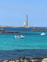 three boats in the water with a lighthouse in the background at Kerletty, la mer, les embruns, à 250 m des plages in Plouguerneau