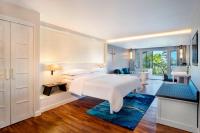 a bedroom with a large white bed and a bathroom at Sheraton Samui Resort in Chaweng Noi Beach